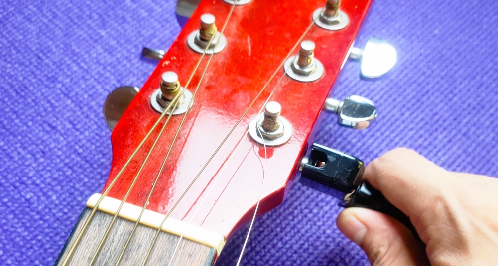 Unwinding the tuning pegs or tuning post using string winder to remove the string.